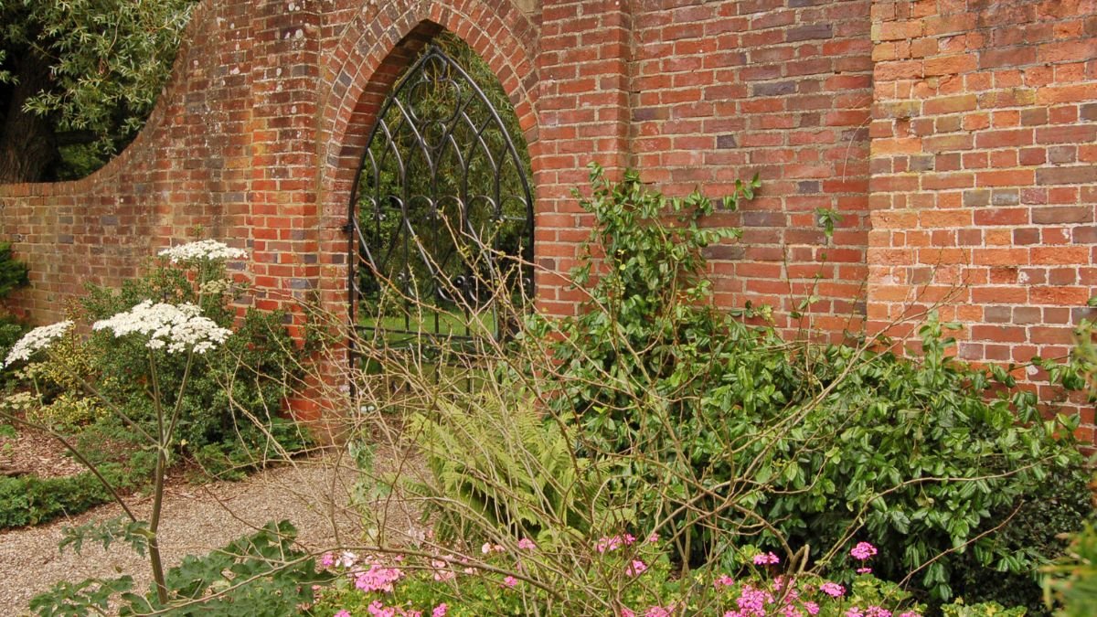 Ein gepflegter Garten mit blühenden Pflanzen und einer Ziegelmauer.