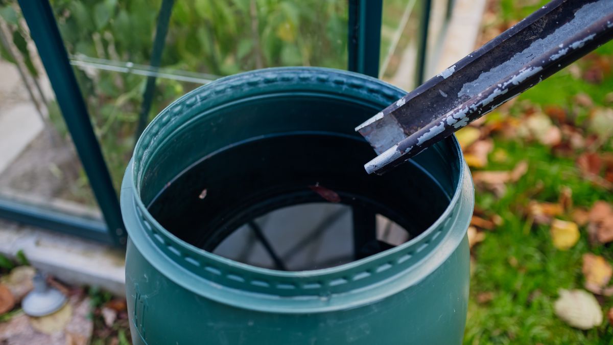 Ein grüner Regenwassertank mit Wasser und einem Schaufelwerkzeug.