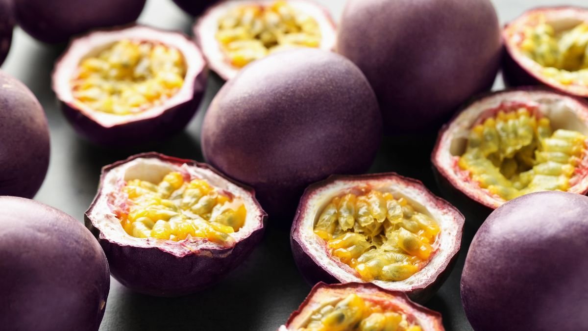 Eine Ansammlung von Passionsfrüchten, einige aufgeschnitten, mit leuchtendem Fruchtfleisch.